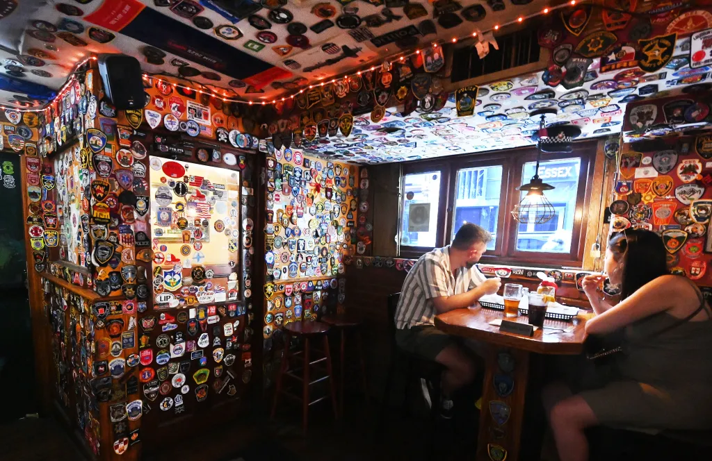 Diners sitting at O'Hara's Restaurant and Pub, with its walls and ceiling covered in first responder patches.