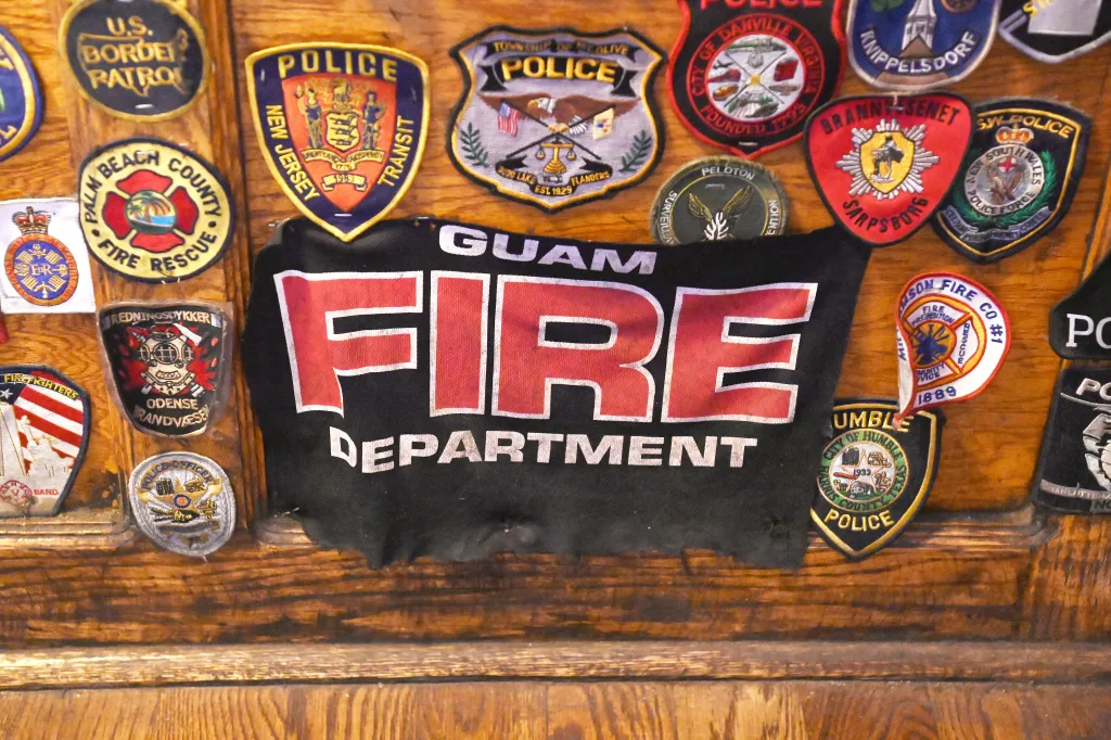 First responder patches, including a banner from the Guam fire department, displayed at O'Hara's Restaurant and Pub.