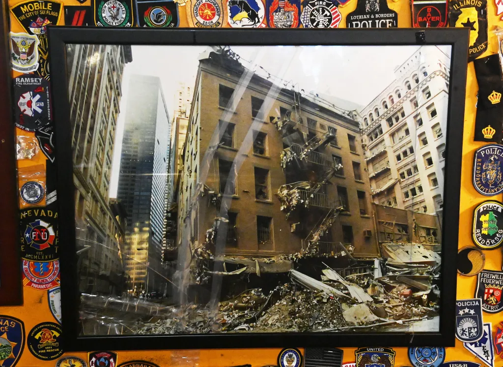A framed photo shows O'Hara's Restaurant and Pub destroyed after 9/11, surrounded by first responder patches.