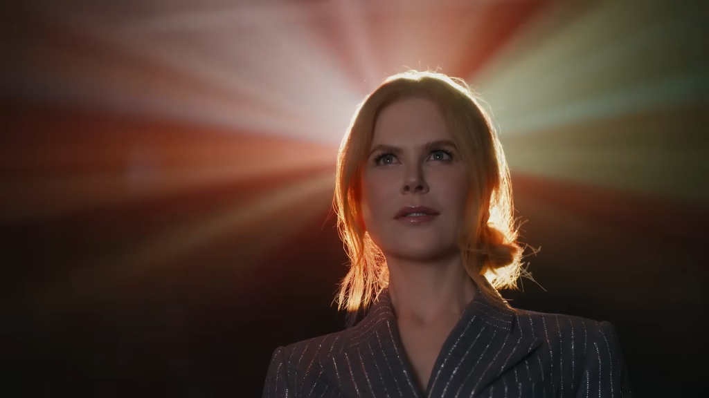 Nicole Kidman in a dark room with a projector light shining from behind her.