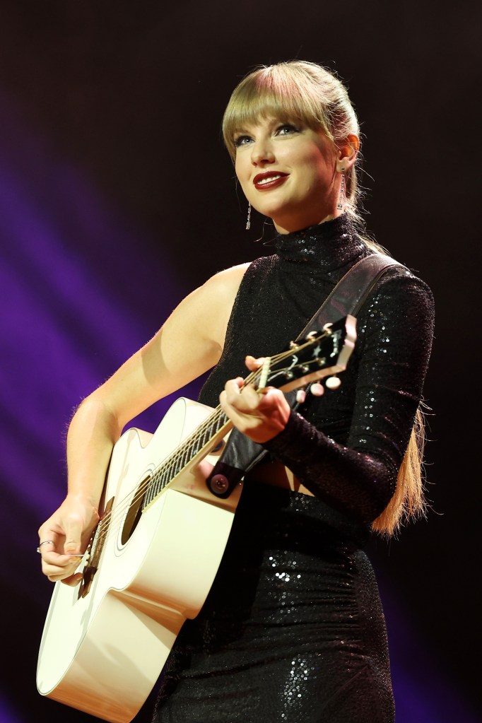 Taylor Swift performing with an acoustic guitar.
