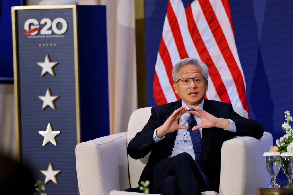 Nvidia CEO Jensen Huang speaking at the G20 Innovation Ministerial summit, with an American flag and a G20 sign in the background.