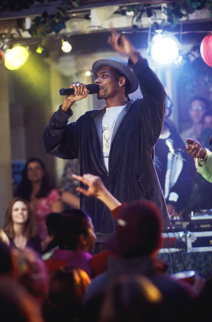 Snoop Dogg singing into a microphone on stage at a party in 2003.