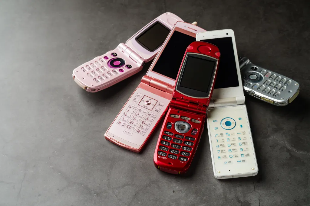 Collage of five open flip phones in various colors and models on a dark background.