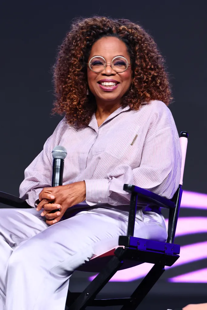 Oprah Winfrey smiling and holding a microphone during a discussion at the 2023 Essence Festival of Culture.