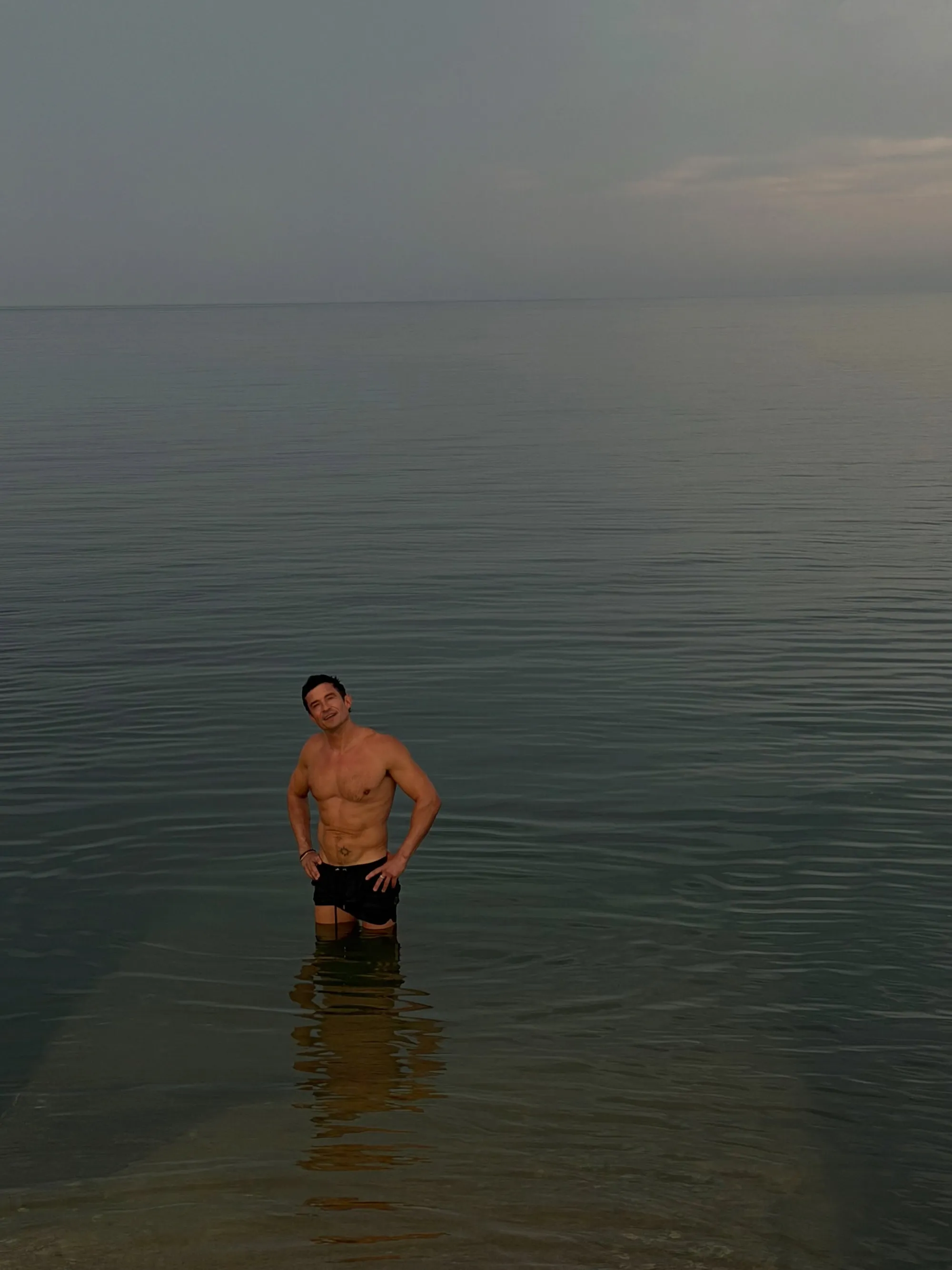 Orlando Bloom standing in the ocean.