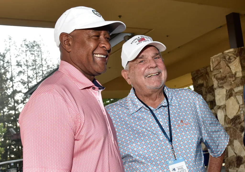 Ozzie Smith and Phil Oates smiling while wearing golf hats and polo shirts.
