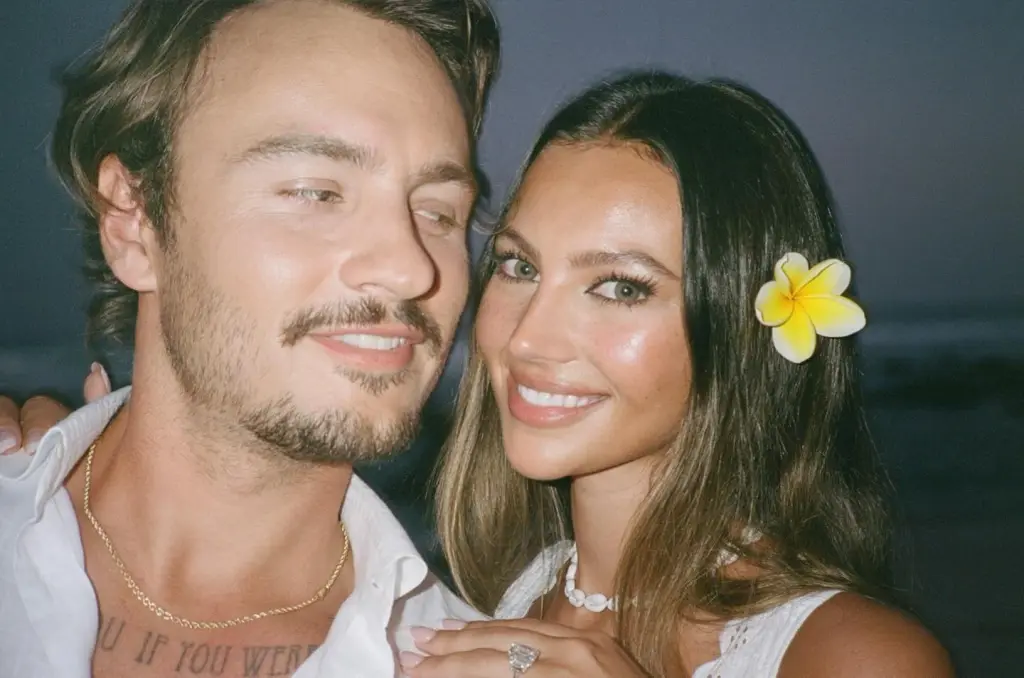 Brandon Lee and Katarina Demetriades smiling, with Demetriades wearing an engagement ring and a flower in her hair.