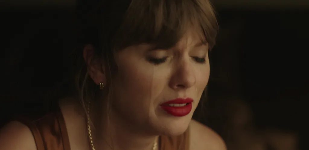 Taylor Swift with her eyes closed, crying with red lipstick and tears streaming down her face.