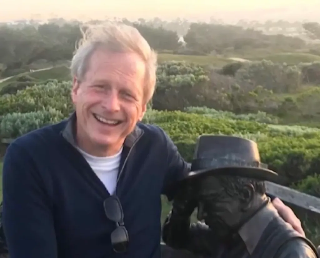 Patrick Seamus Mulderrig smiling next to a bronze statue.