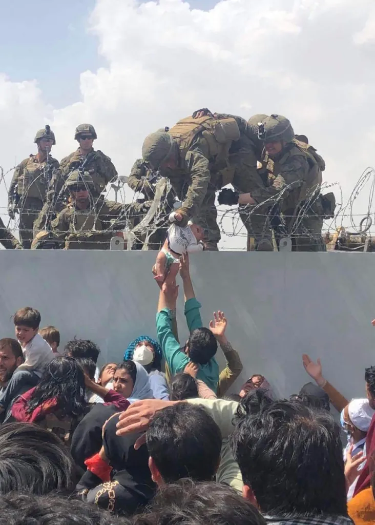 A US Marine grabs an infant over a fence of barbed wire during an evacuation at Hamid Karzai International Airport in Kabul on August 19, 2021.