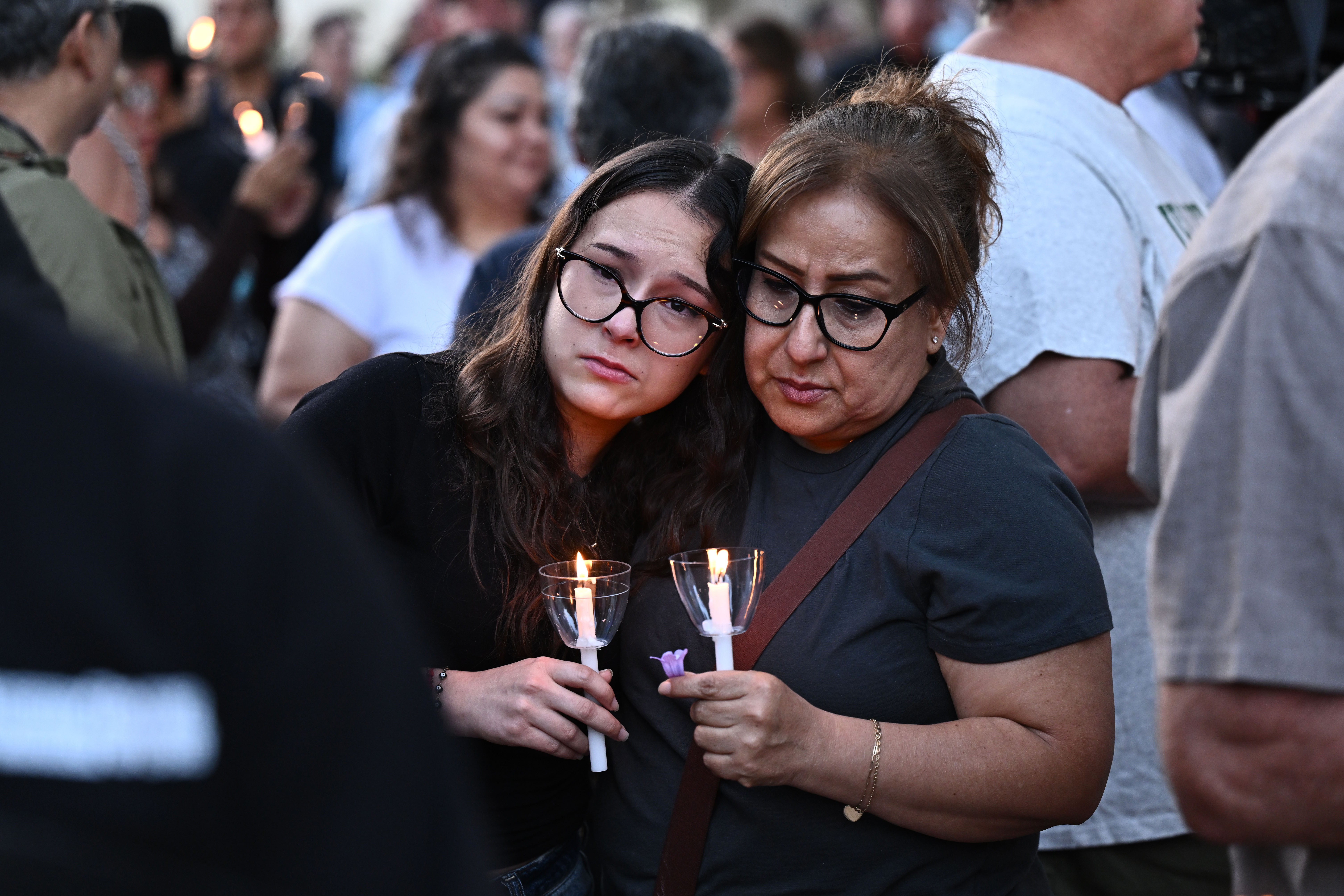 Two women hold lit candles during a vigil.