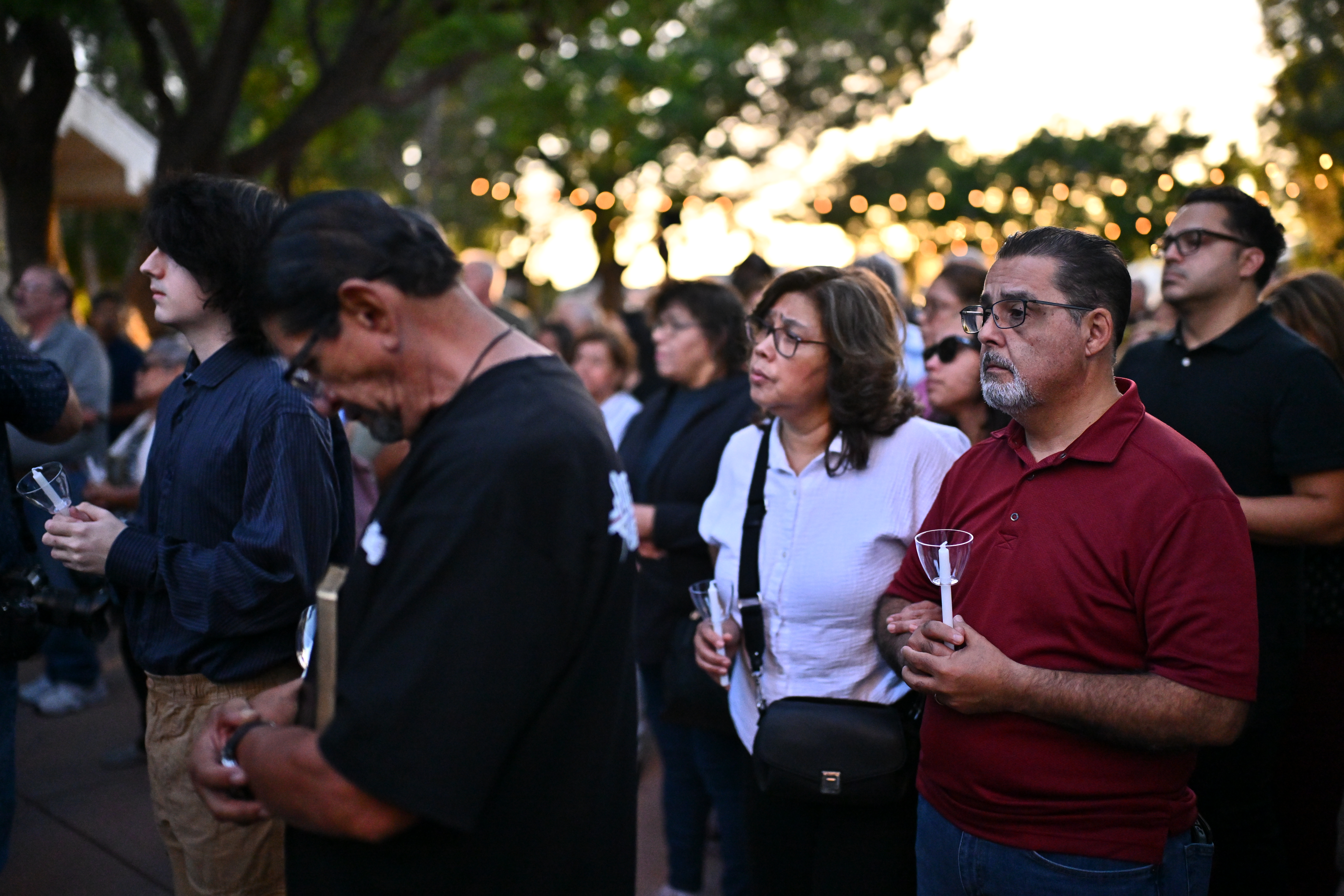 People attend a vigil holding candles for those who died in a Metro bus accident and news helicopter crash.