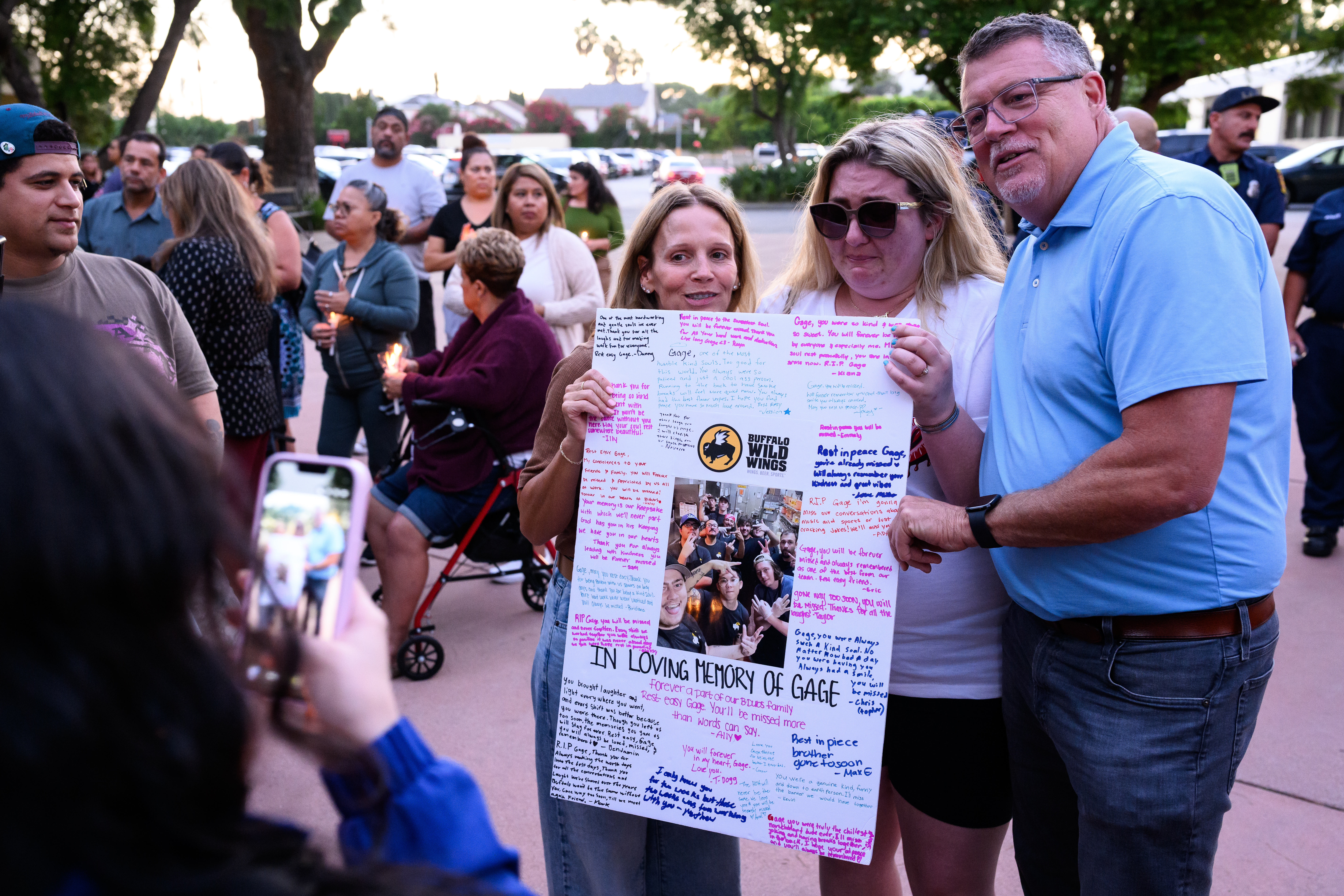 People give a poster made to honor Gage Weida to his family at a vigil in Los Angeles.