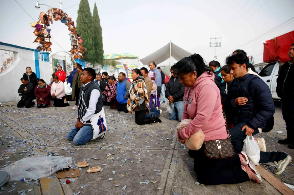People pray on their knees after a fireworks explosion in Santa Maria Canchesda.