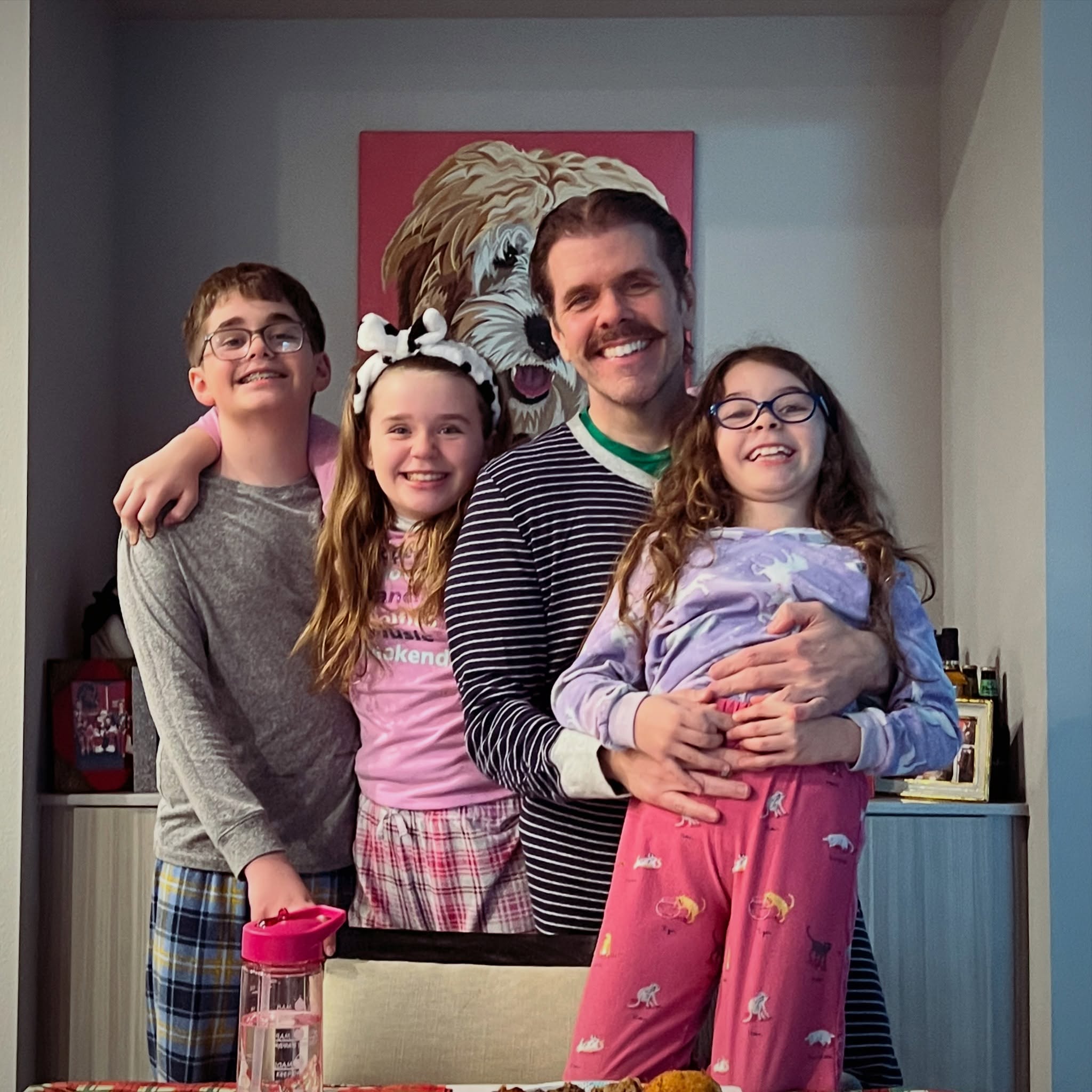 Perez Hilton and his three children smiling together in pajamas.