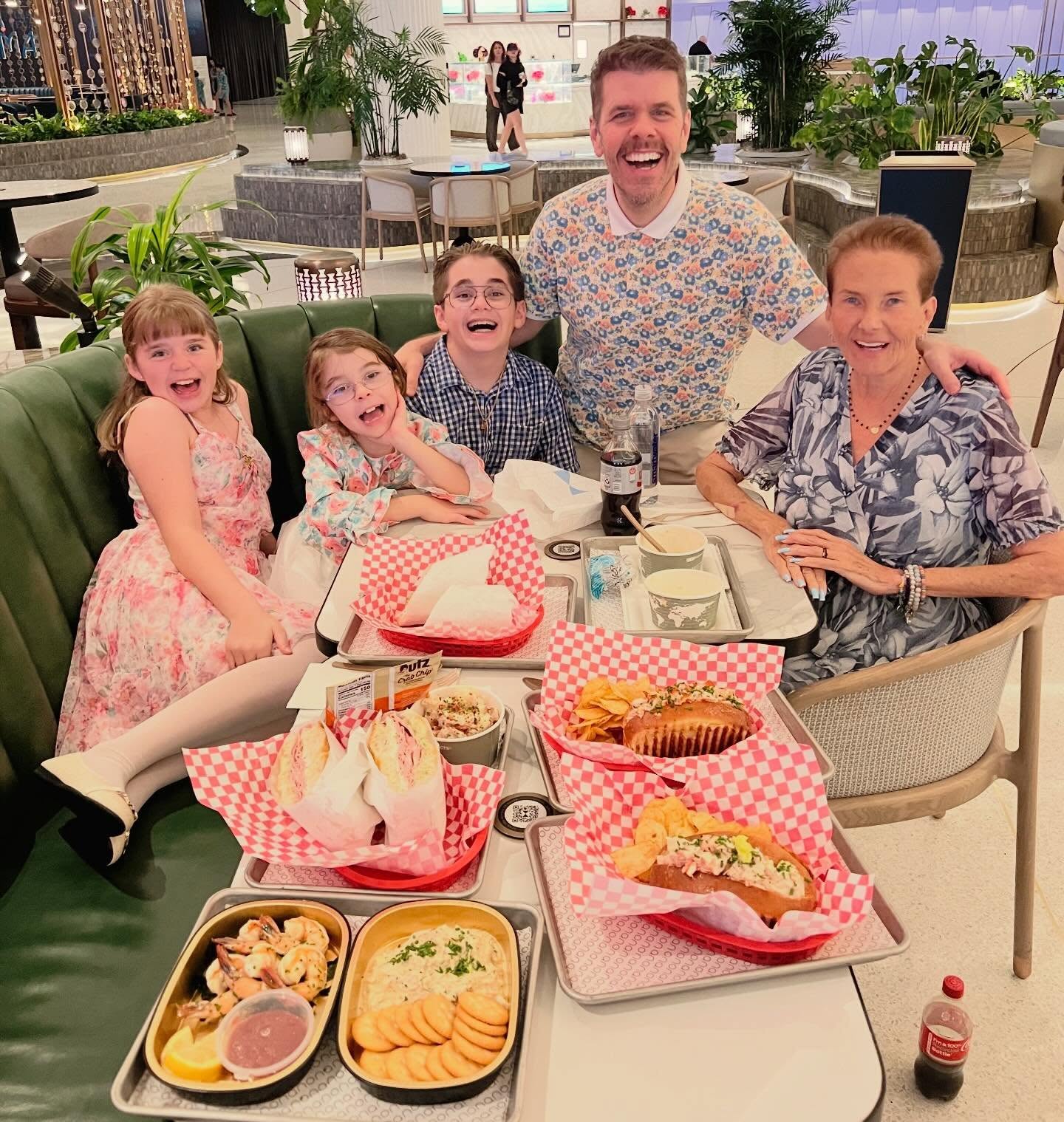 Perez Hilton with his mother and three children smiling around a table full of food.