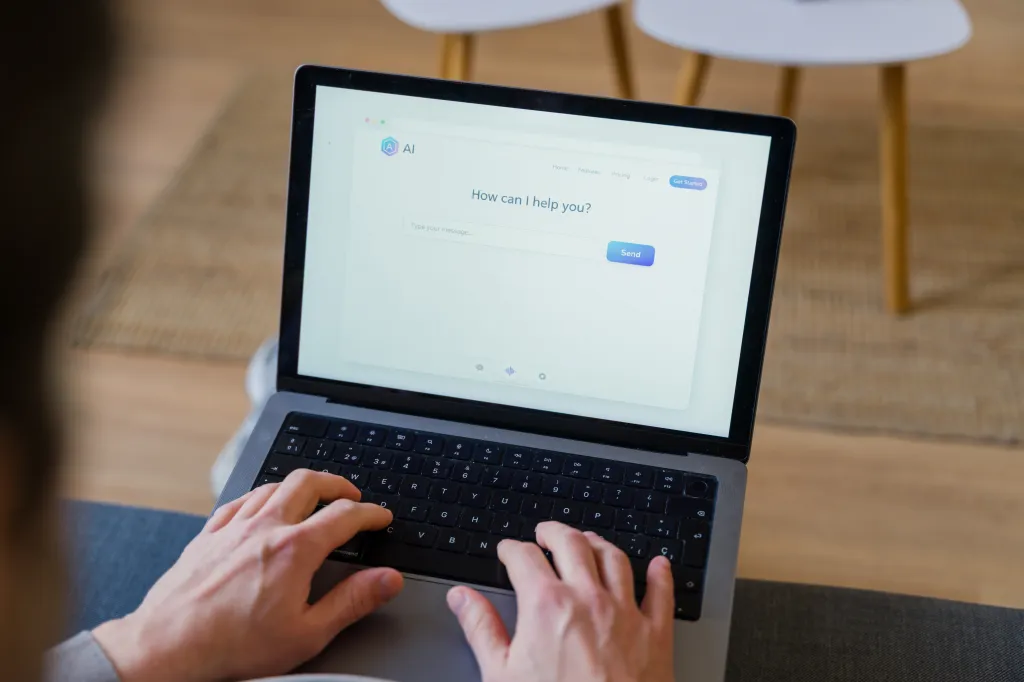 Person typing a message into an artificial intelligence chatbot on a laptop screen.