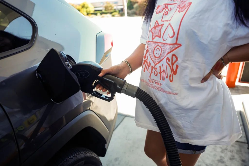 A person pumping gas into their car at a 76 gas station.