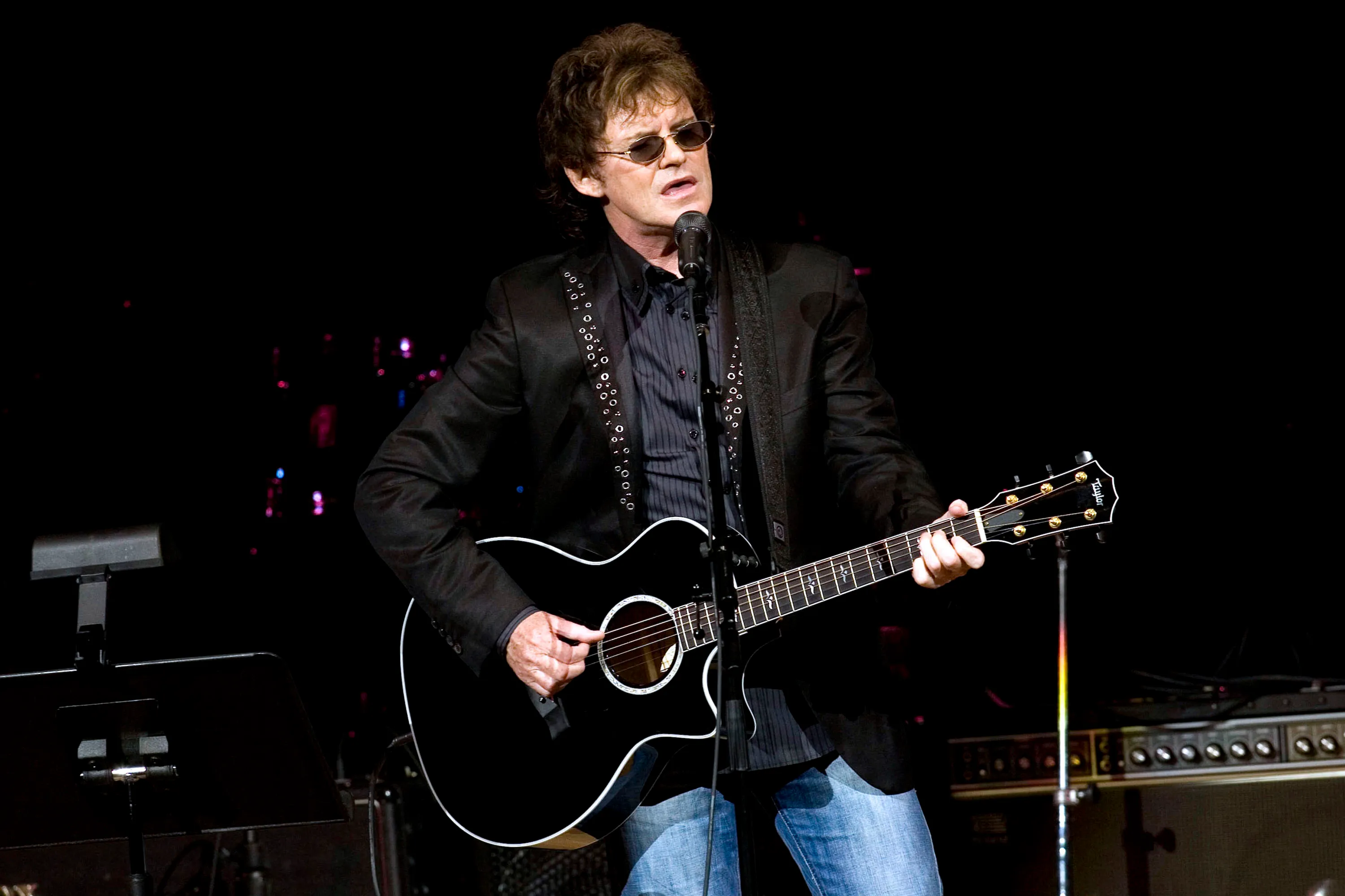Pete Byrne performing with a black acoustic guitar.