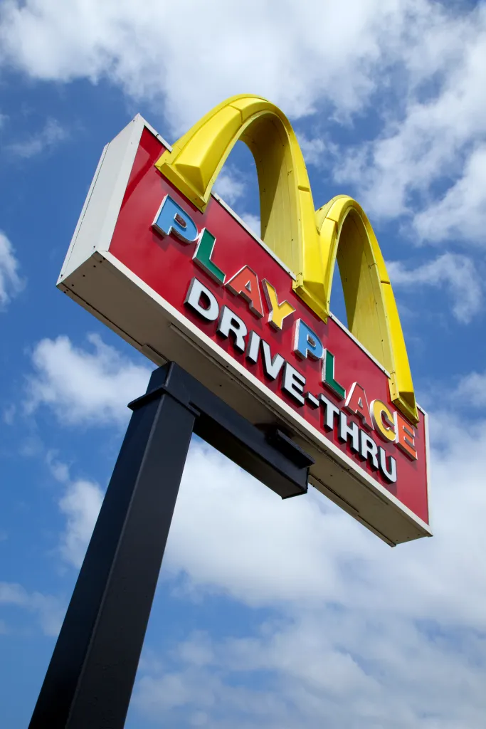 A low-angle view of a McDonald's sign with yellow arches, red background, and 