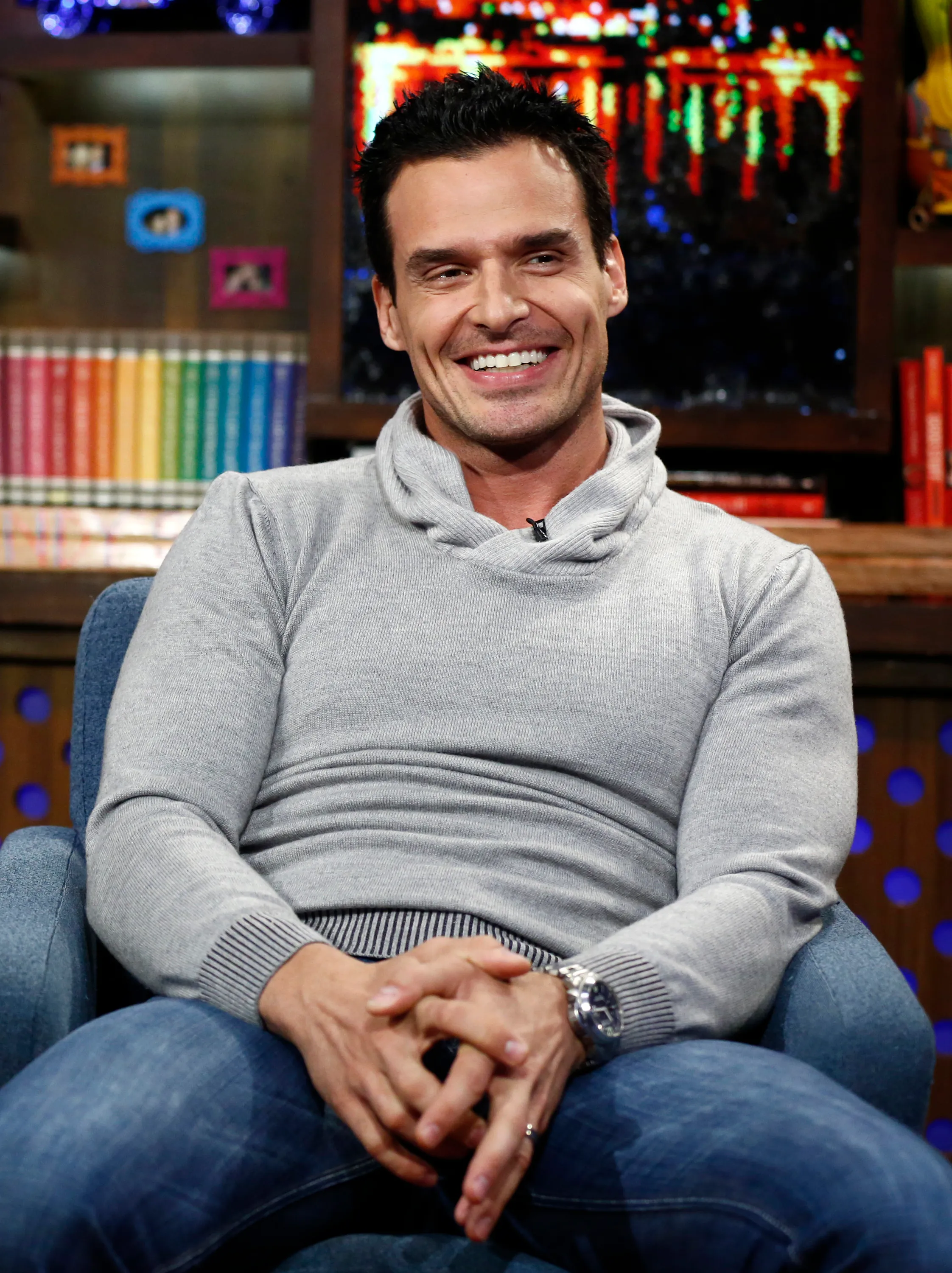 Antonio Sabato Jr. smiles while seated in a gray sweater and blue jeans.