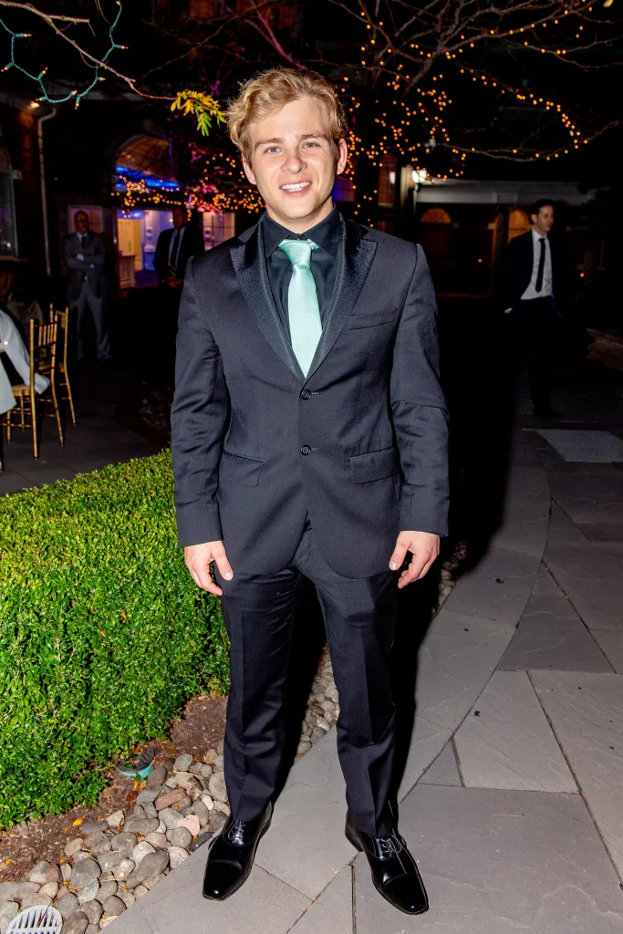 Jonathan Lipnicki poses in a black suit with a mint green tie at the J100 Gala.