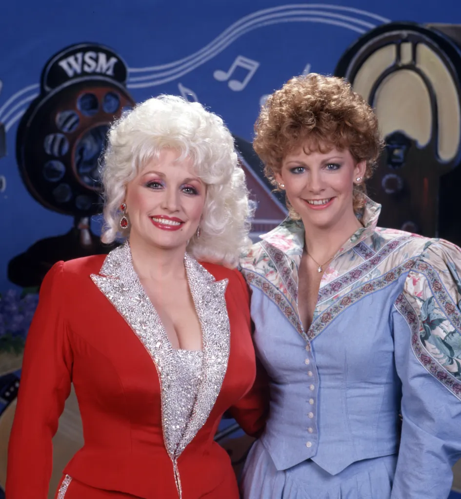 Dolly Parton and Reba McEntire posing together at the 60th Anniversary of the Grand Ole Opry.