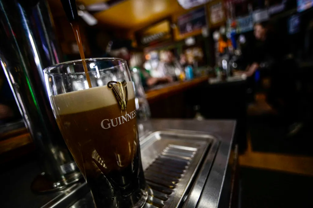 A Guinness beer being poured into a branded glass.