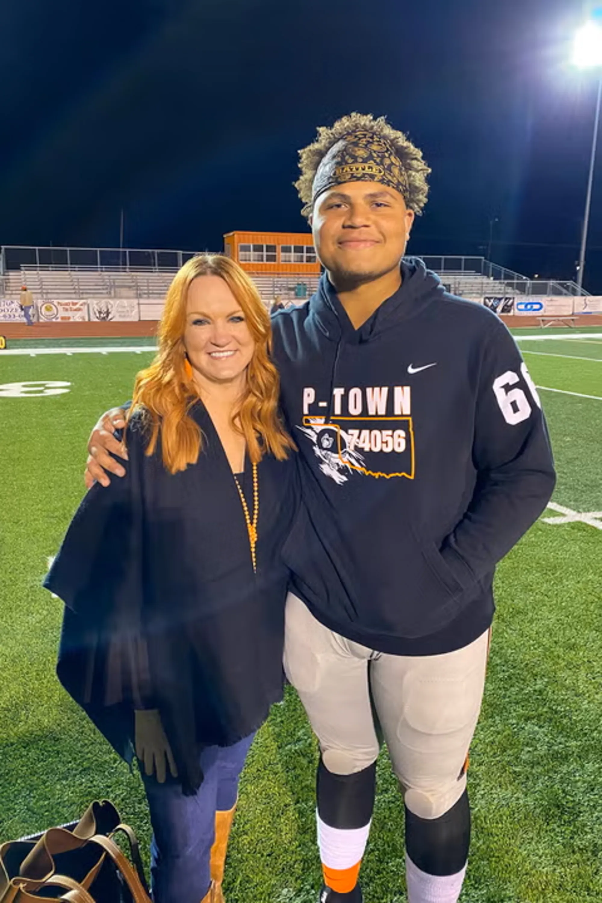 Ree Drummond smiling with her arm around her son, Todd, on a football field at night.