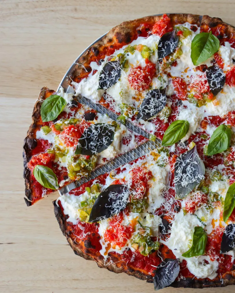 A pizza from Pizzeria Sei in Los Angeles, topped with red sauce, fresh cheese, green peppers, and basil.