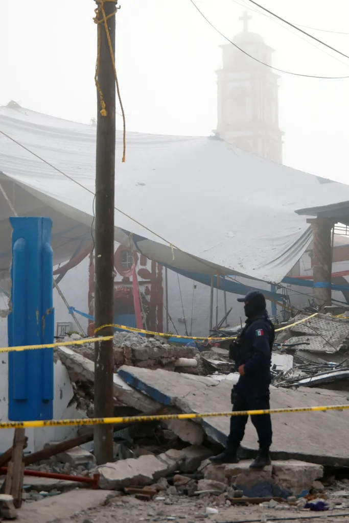 A police officer stands among debris following a fireworks explosion in Santa Maria Canchesda, Mexico.