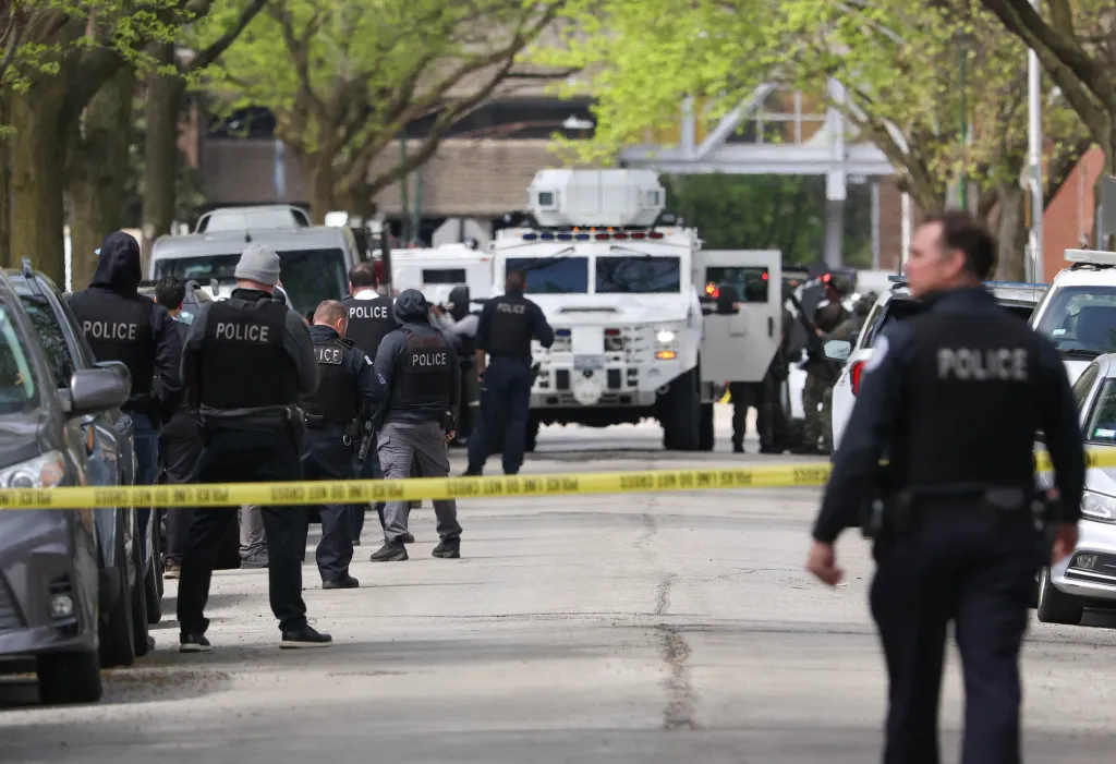 Police officers and tactical vehicles at the scene of a shooting.