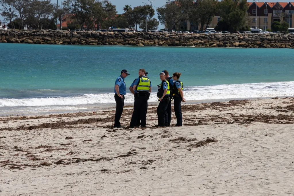 Police stand on Sorrento Beach in Perth, Australia, on Friday after a suspected fatal shark attack.