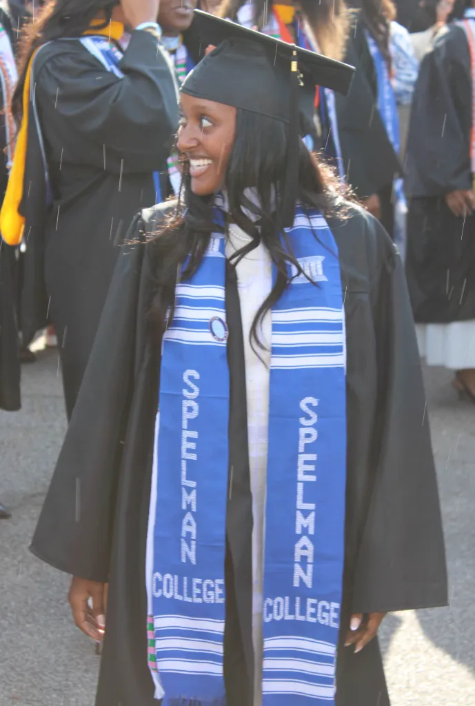 Zahara Jolie-Pitt in a black graduation gown with a blue and white Spelman College stole.