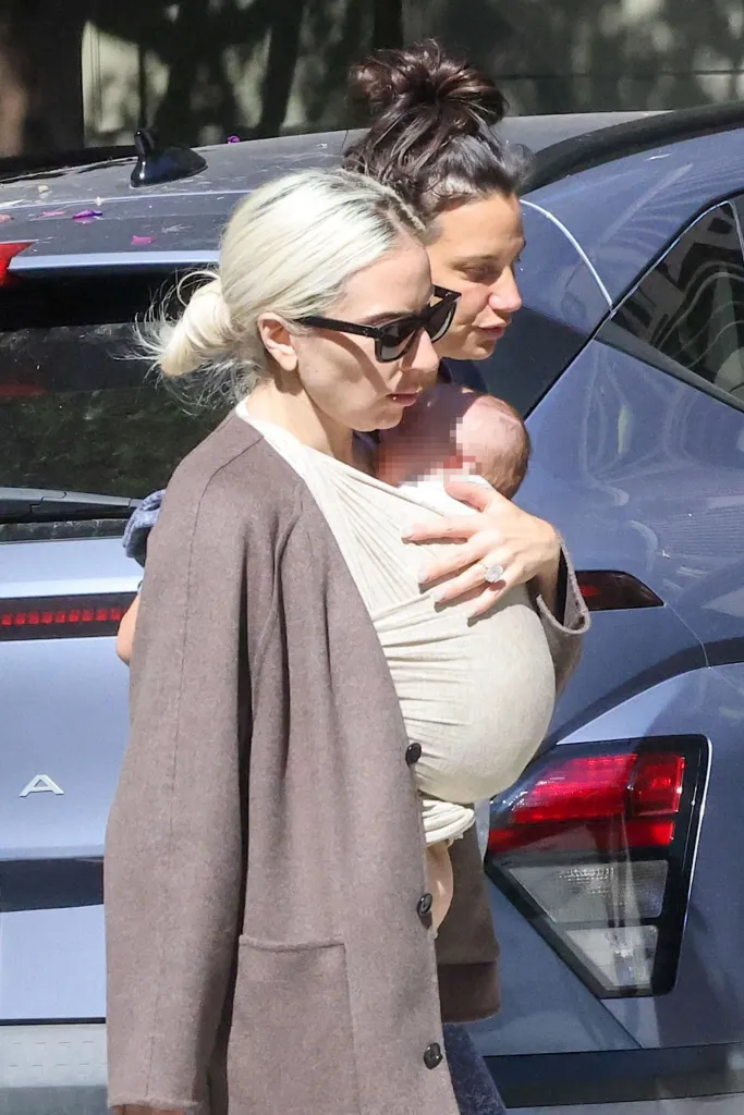 Lady Gaga walking with a baby in a carrier and Michael Polansky beside her.