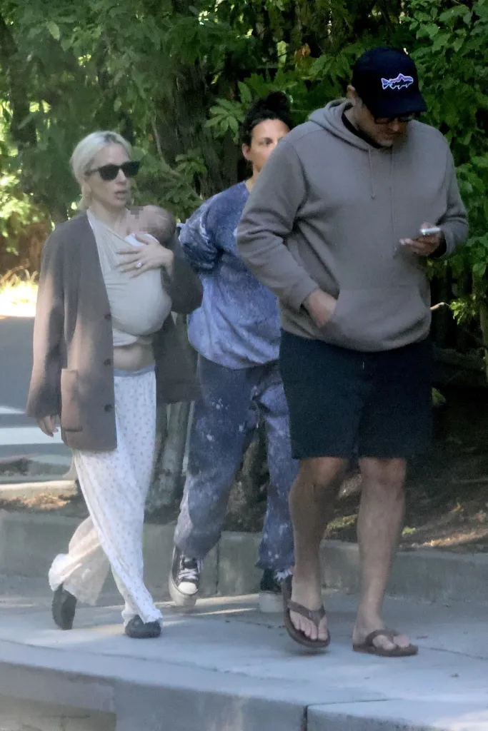 Lady Gaga walking with her baby in a carrier and Michael Polansky.