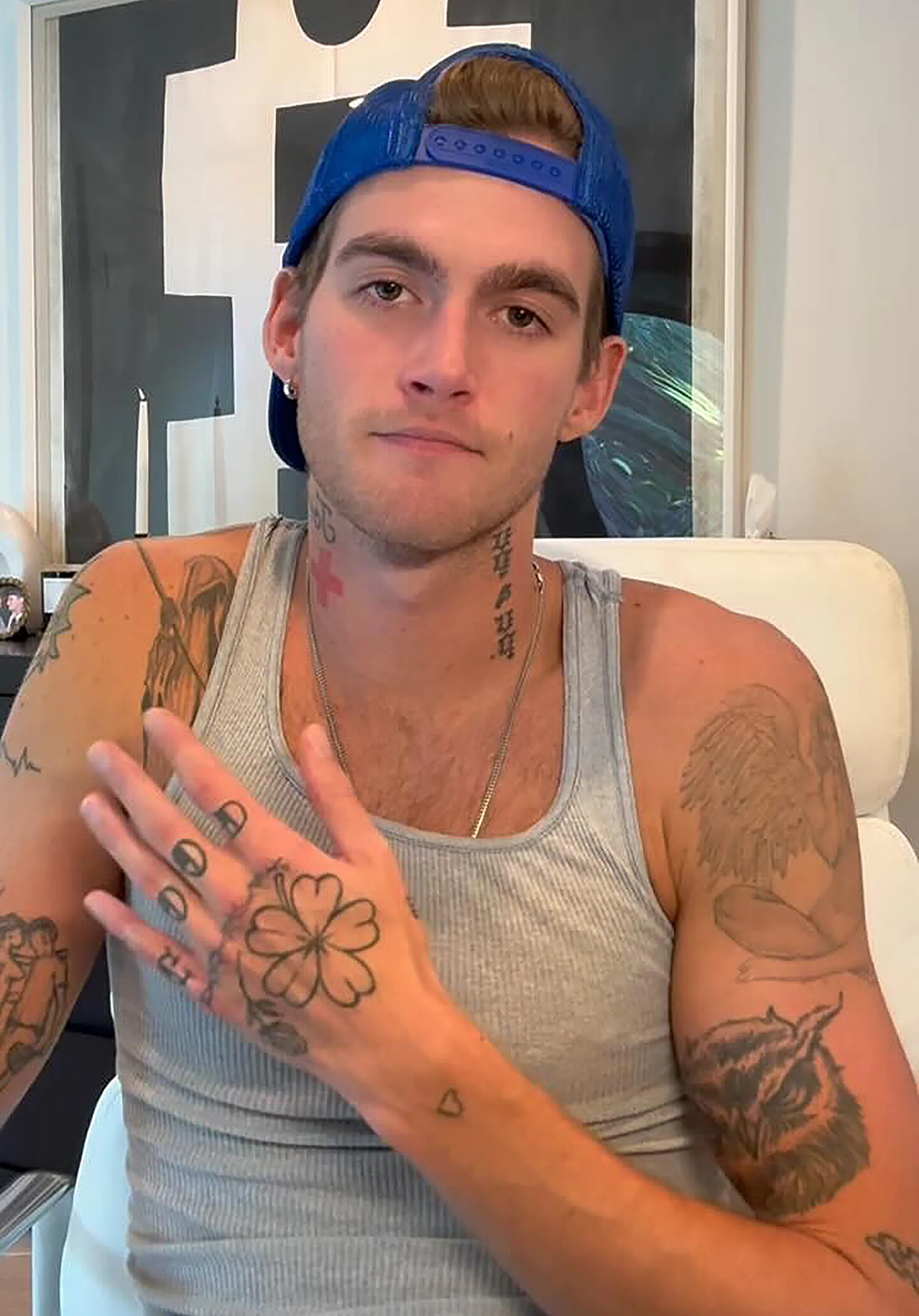 Presley Gerber wearing a blue hat and gray tank top, displaying his arm and hand tattoos.