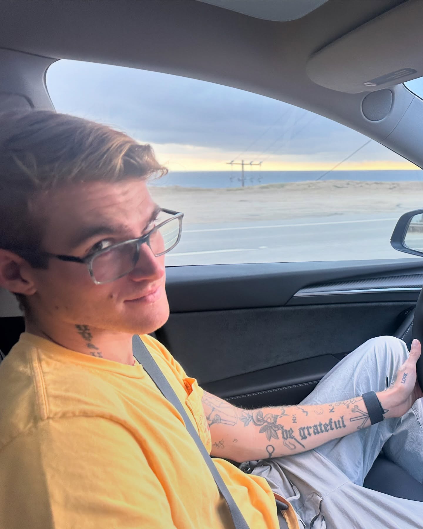 Presley Gerber in the driver's seat of a car, with the ocean in the background.