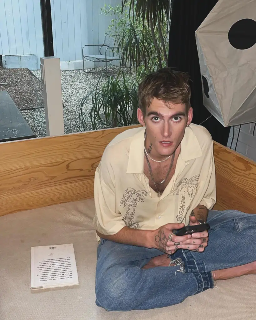 Presley Gerber, model son of Cindy Crawford and Rande Gerber, looking up while holding a phone.