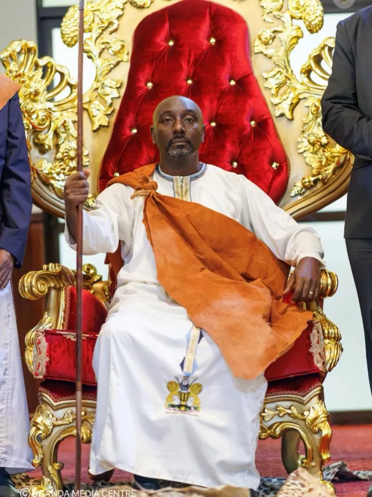Prince Edward Rukidi Kijanangoma Nyabongo I seated on a red and gold throne.