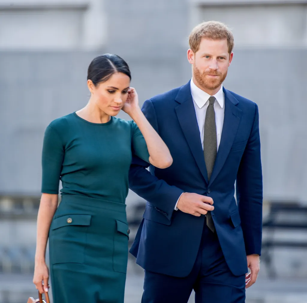 Prince Harry in a navy suit and Meghan Markle in a green dress.