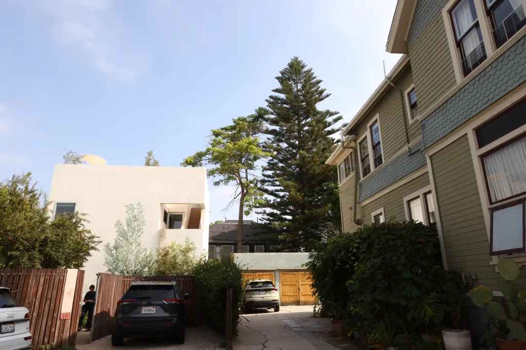 The GRANADA residence, a modern white building, and an older green house, are connected by a shared driveway in Los Angeles.