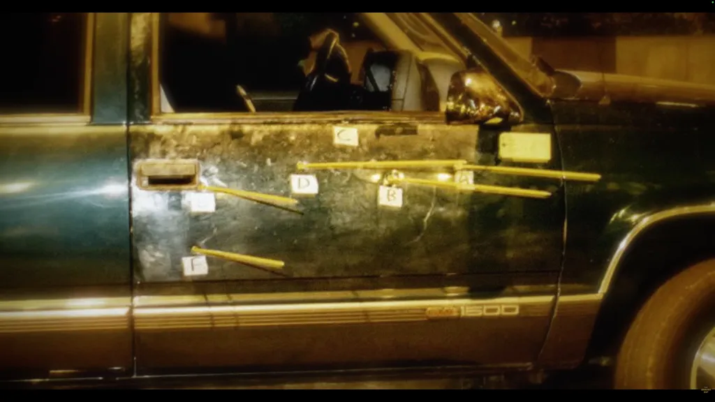 Bullet-riddled green pickup truck with markers indicating bullet trajectories.