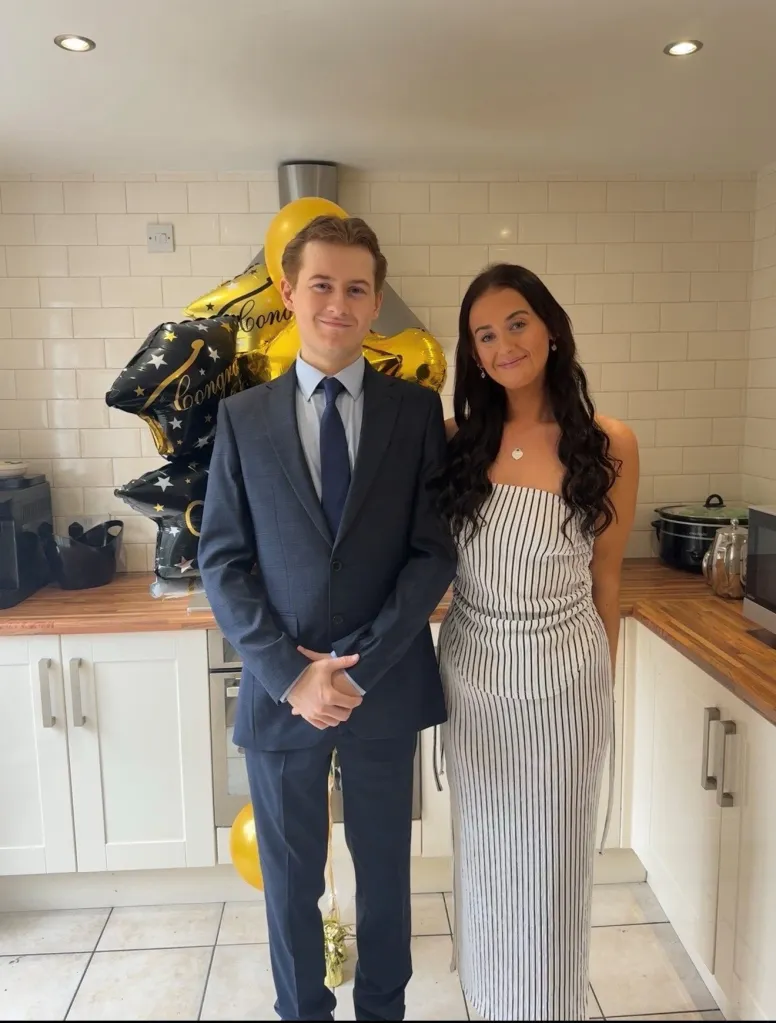 Rachel and Harry Ware stand side by side in a kitchen, with black and gold 
