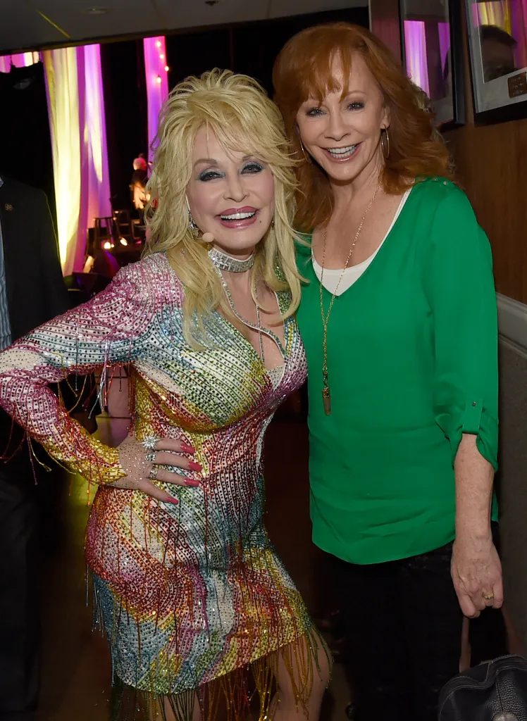 Dolly Parton and Reba McEntire smiling at the camera.