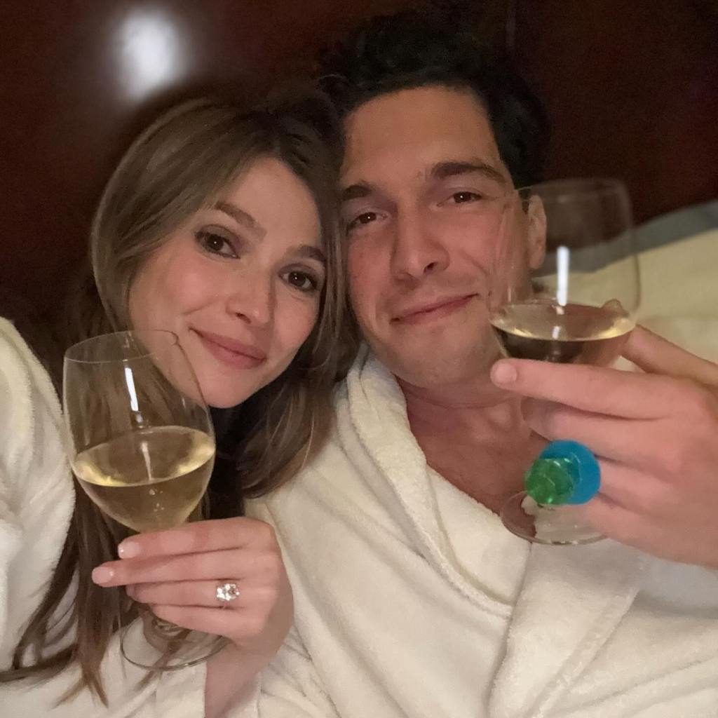 Will Reeve and his wife Amanda toast with glasses of white wine while wearing white bathrobes.