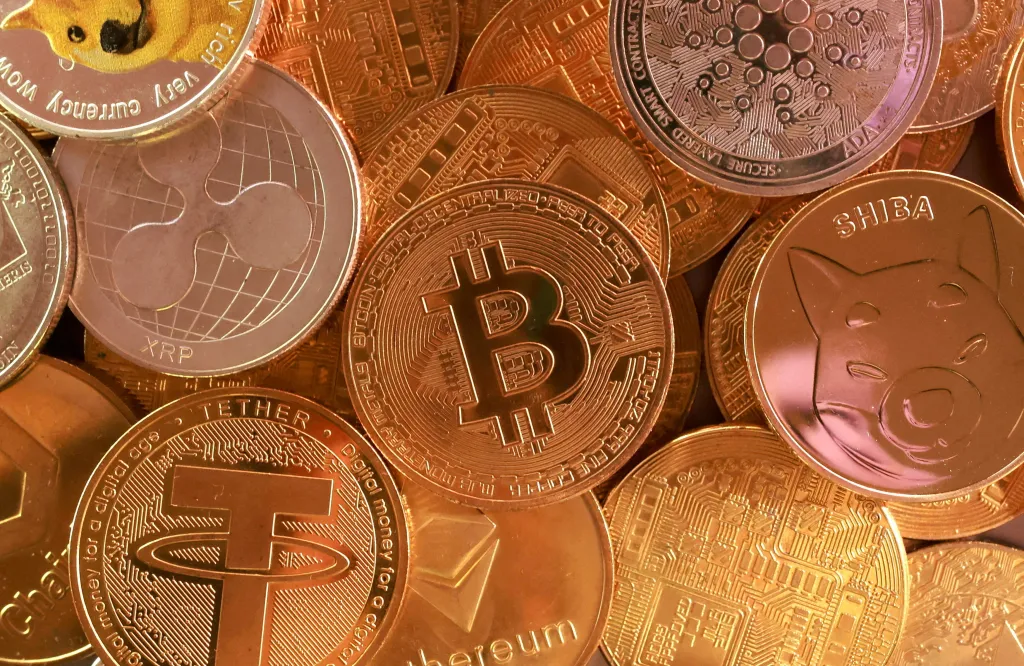 Illustration of various cryptocurrencies including Bitcoin, Ethereum, Ripple, Tether, Dogecoin, Cardano, and Shiba Inu coins.