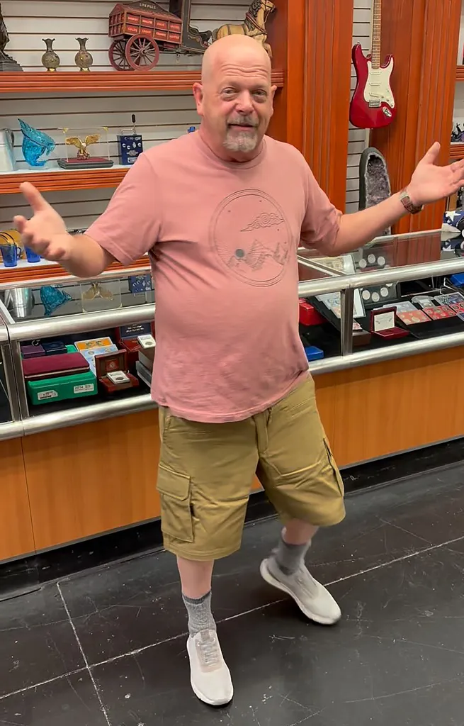 Rick Harrison standing in front of display cases, gesturing with both hands.