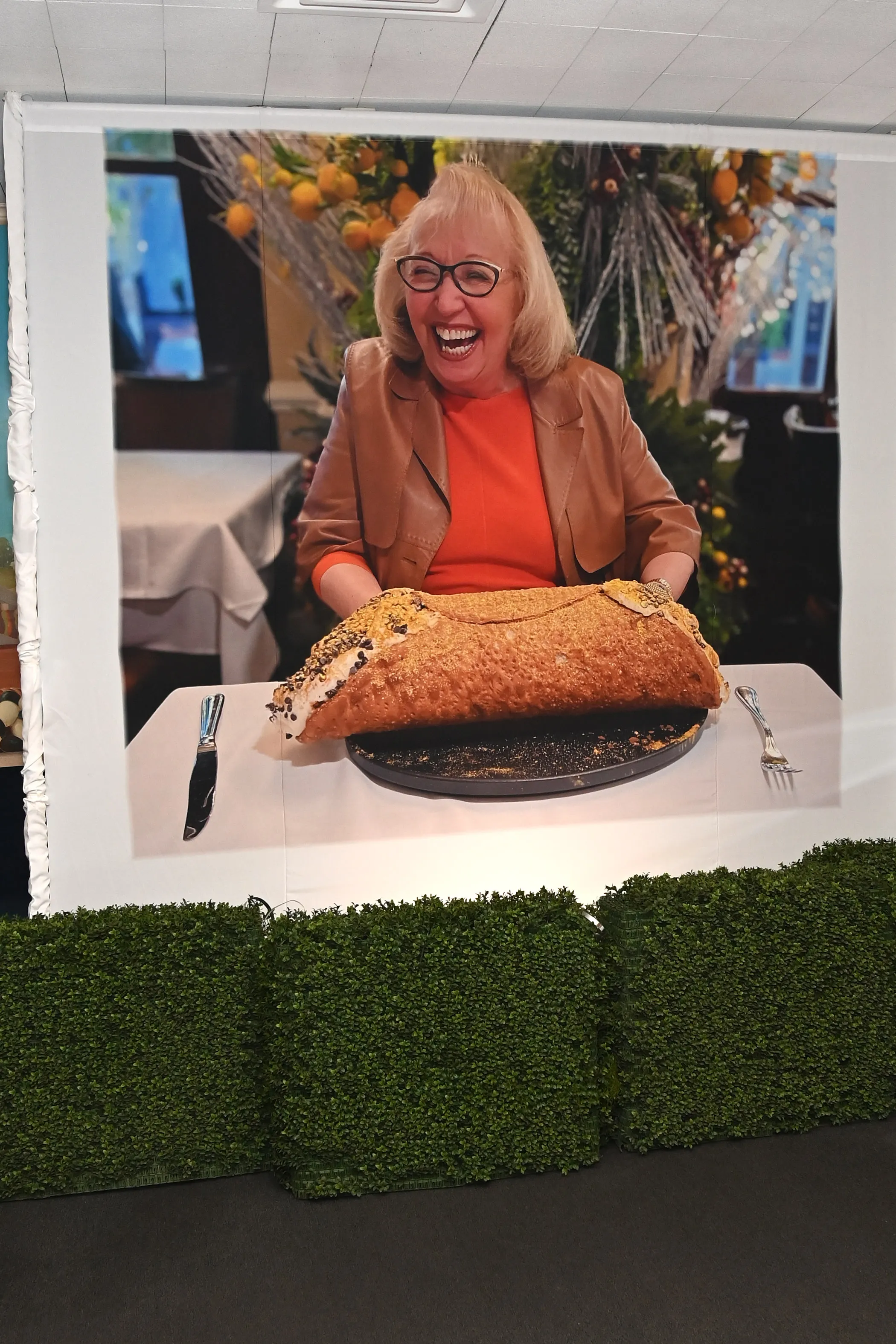 A banner featuring a large photo of a smiling Marion Scotto with a massive cannoli on a table in front of her.